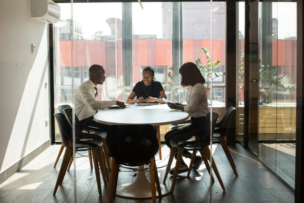 pexels-photo-9488842-9488842 Three professionals collaborating in a modern office boardroom setting during daylight.