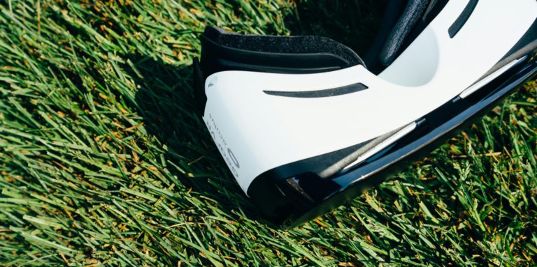 A close-up shot of VR goggles placed on a green grass lawn under sunlight.